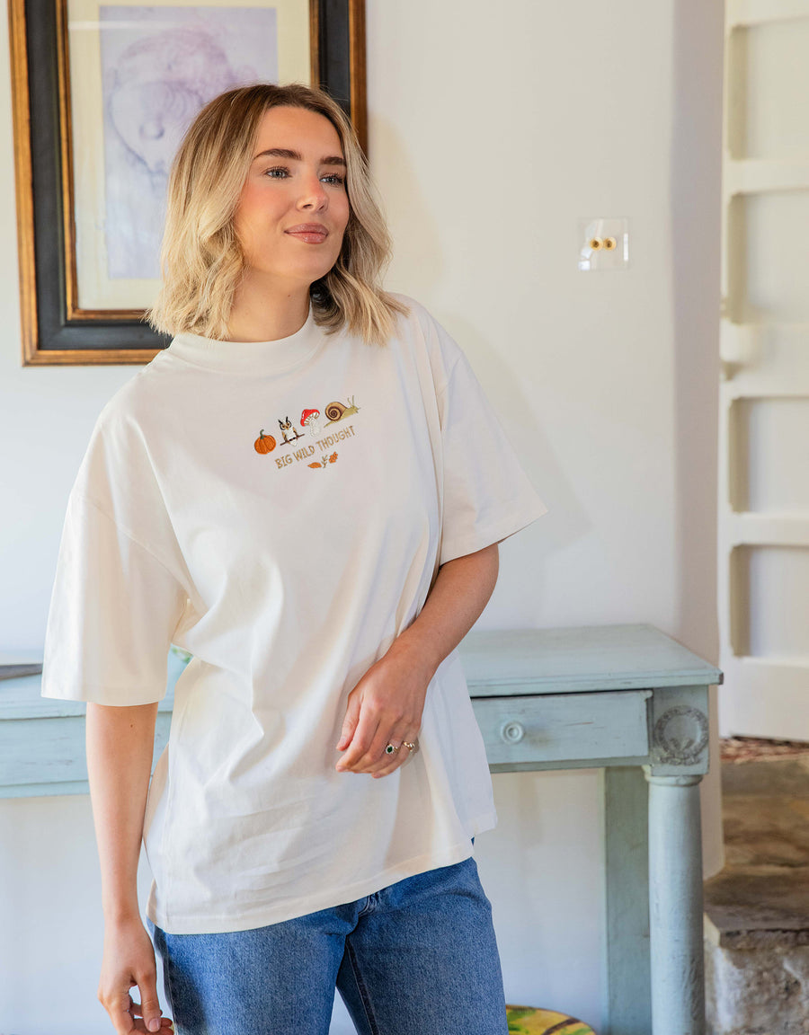 Cosy Autumn embroidered unisex oversized tee in Cream worn by a model, with a pumpkin, owl, toadstool and snail design