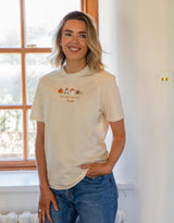 Cosy Autumn embroidered unisex t-shirt in Natural worn by a model, with a pumpkin, owl, toadstool and snail design