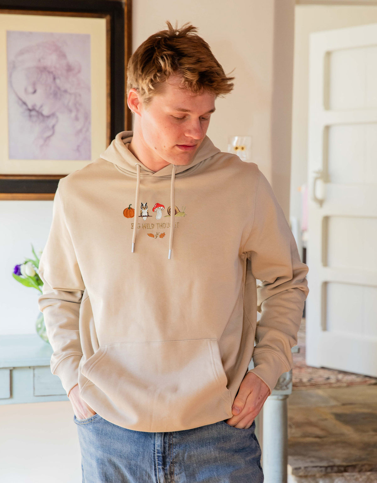 Cosy Autumn embroidered unisex hoodie in Sand worn by a model, with a pumpkin, owl, toadstool and snail design