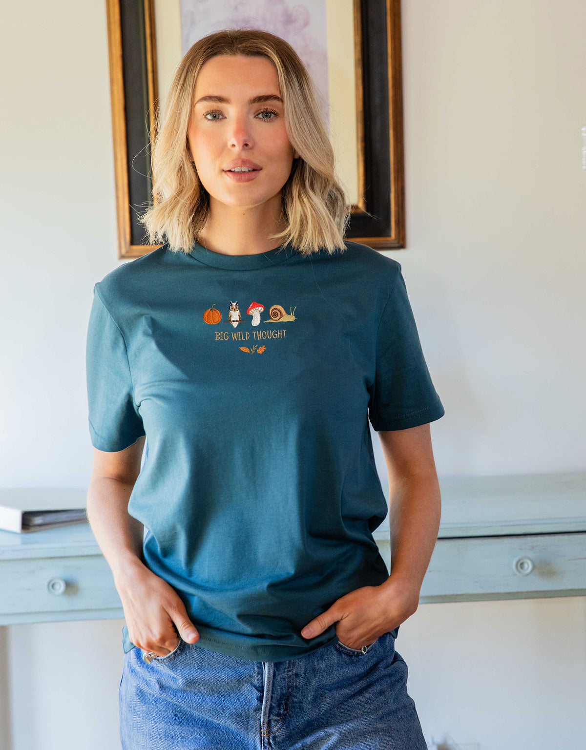 Cosy Autumn embroidered unisex t-shirt in Steel Blue worn by a model, with a pumpkin, owl, toadstool and snail design