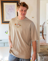 Cosy Autumn embroidered unisex oversized tee in Stone worn by a model, with a pumpkin, owl, toadstool and snail design